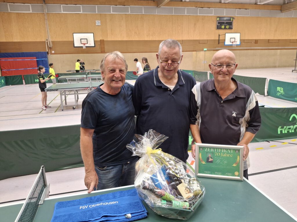 Rolf Lohöfer mit Zertifikat zum 70. Geburtstag in der PSV-Halle, daneben zwei Vereinskameraden